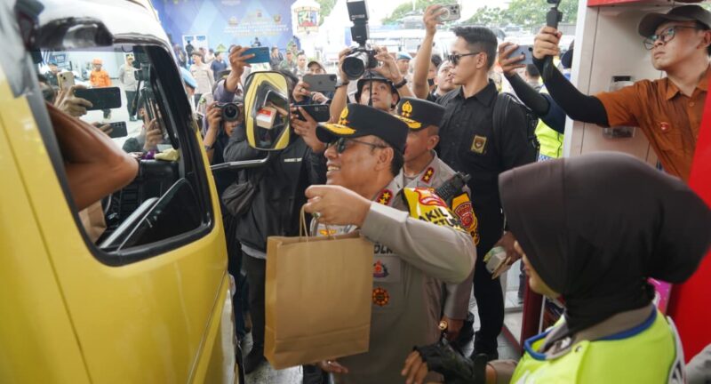 Personel Polisi Wanita (Polwan) bersama prajurit Wanita TNI membagikan paket sembako serta makanan kepada para pemudik yang melintas di Pos Terpadu KM 57.